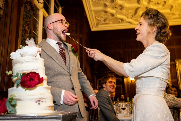 Bride feeds groom wedding cake on big knife at Rothamsted Manor
