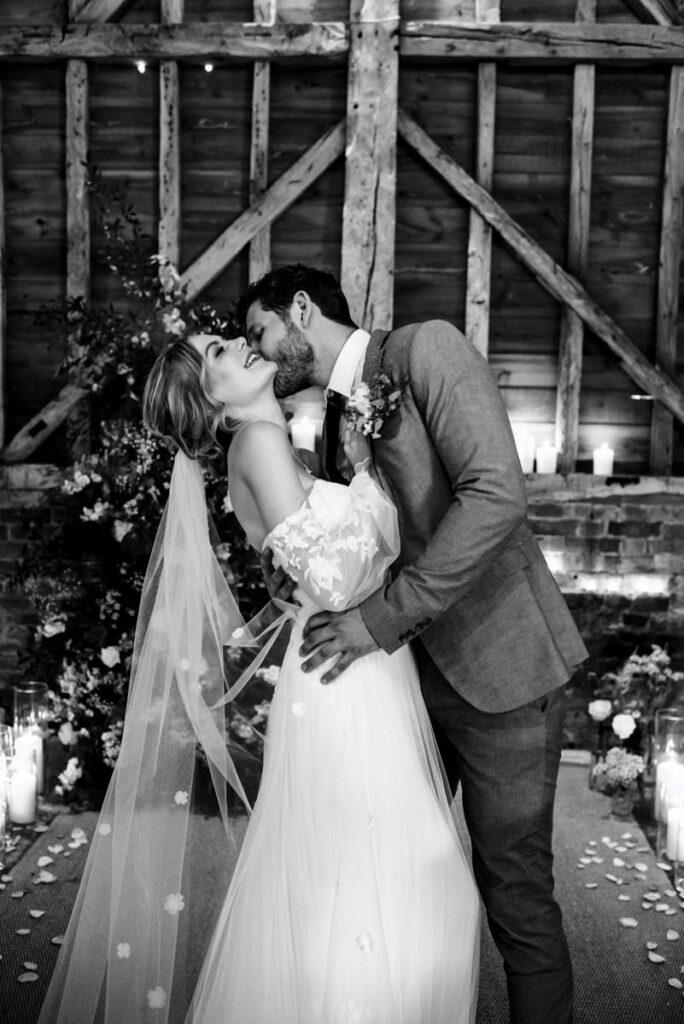 Groom kisses bride on the neck at Milling Barn