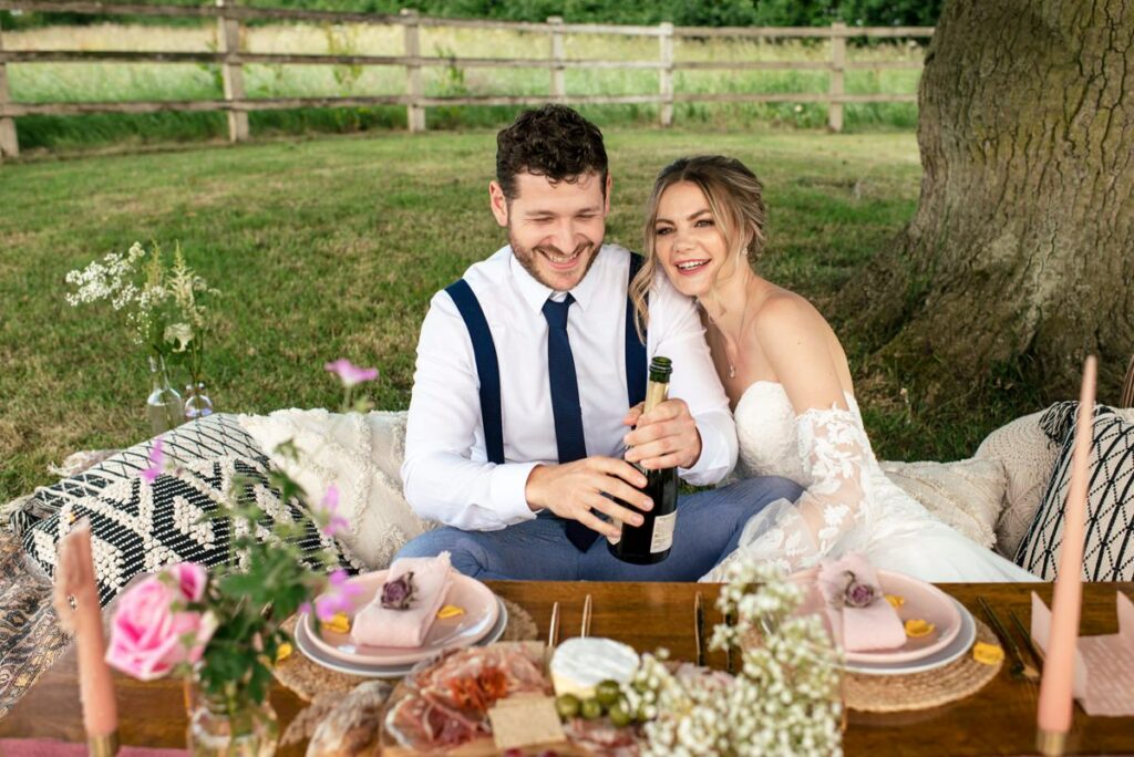 Bride and groom pop champagne at Milling Barn