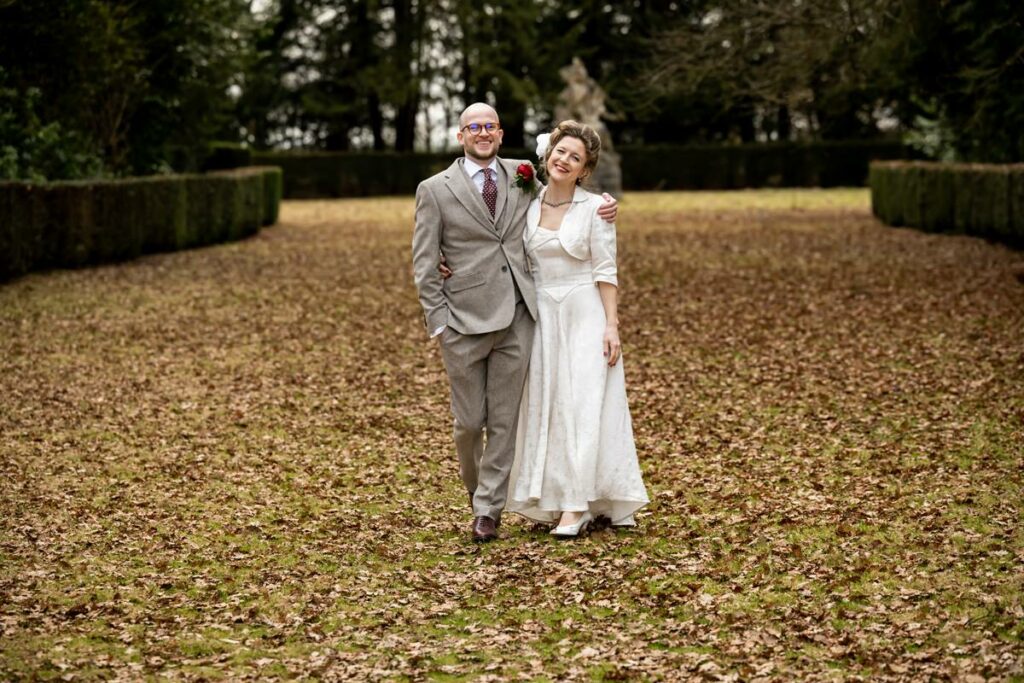 Bride and groom walk down Rothamsted Manor avenue in autumn
