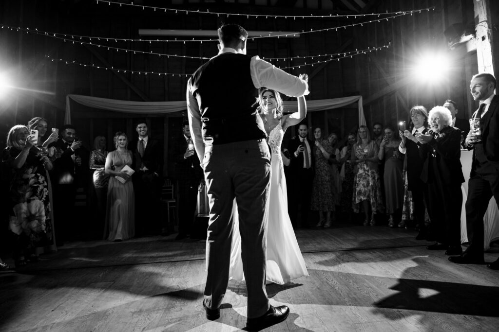 Bride smiles at groom during Tewinbury first dance in black and white photo
