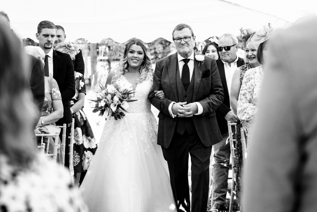 Bride and father walk down aisle at home wedding ceremony