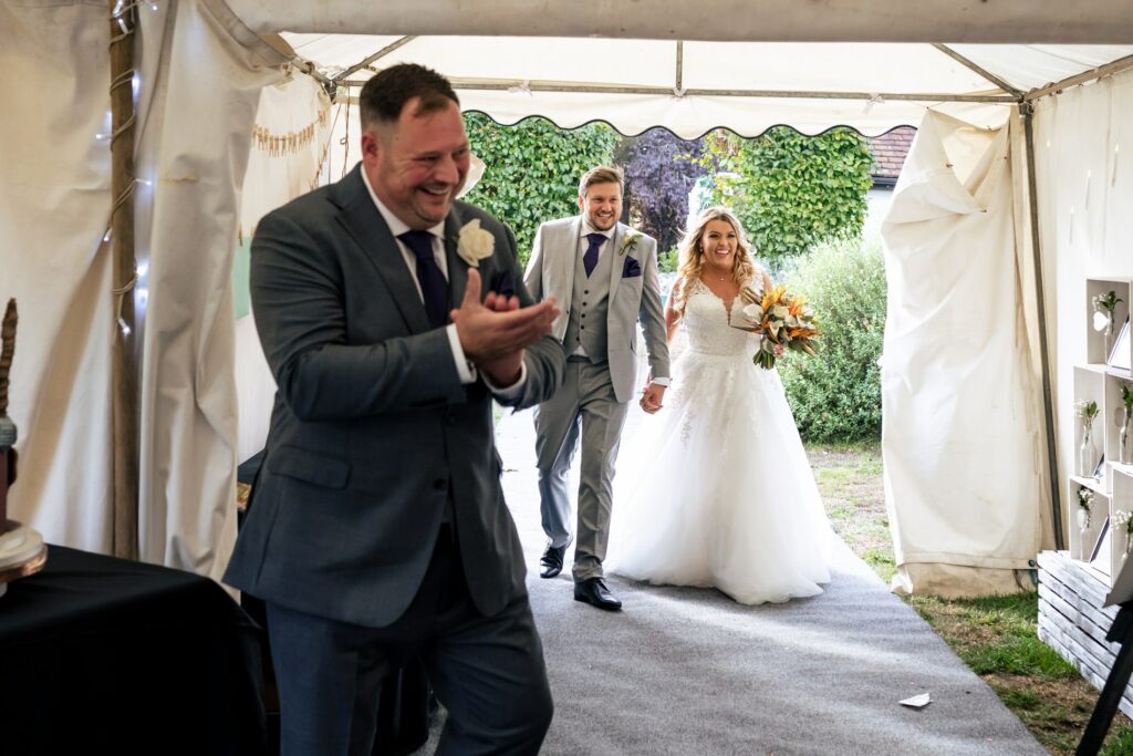Bride and groom enter marquee at home