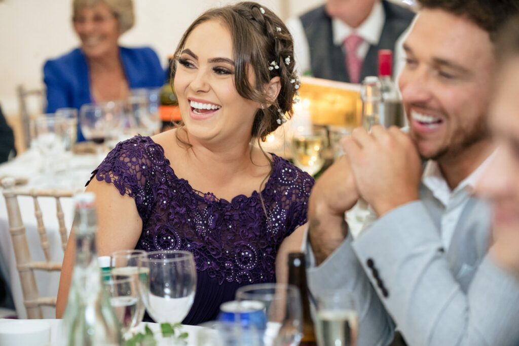 Bridesmaid laughs during wedding speeches in marquee wedding