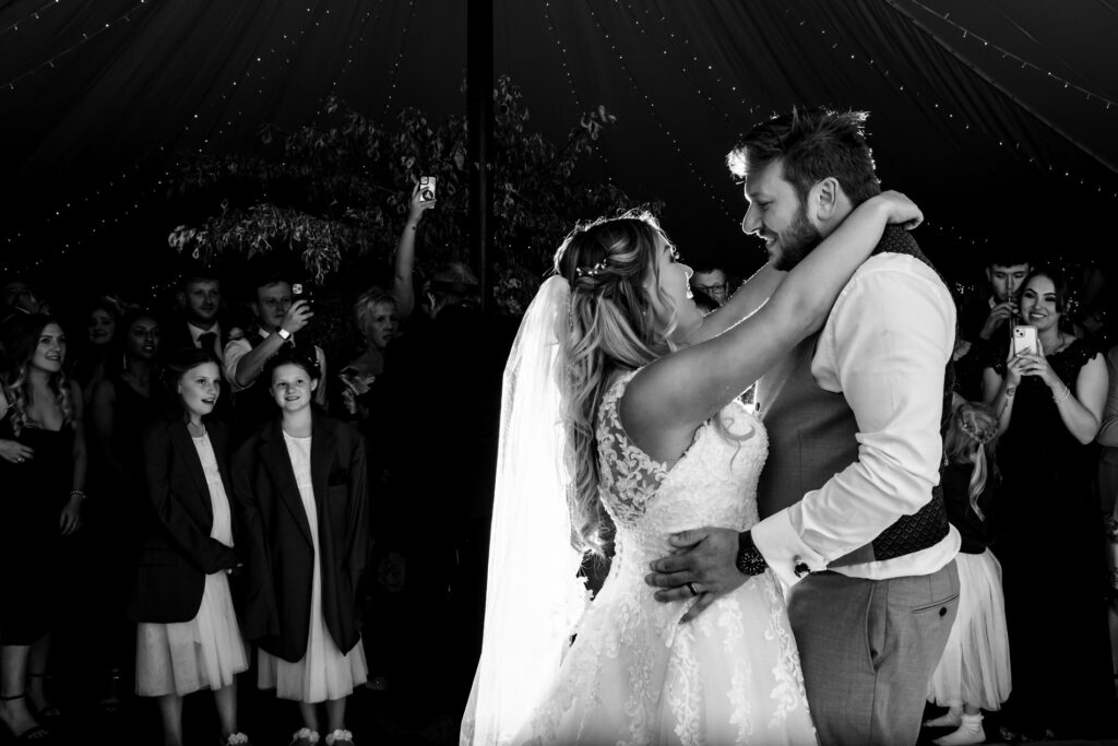 Bride and groom enjoy first dance watched by bridesmaids wearing suit jackets