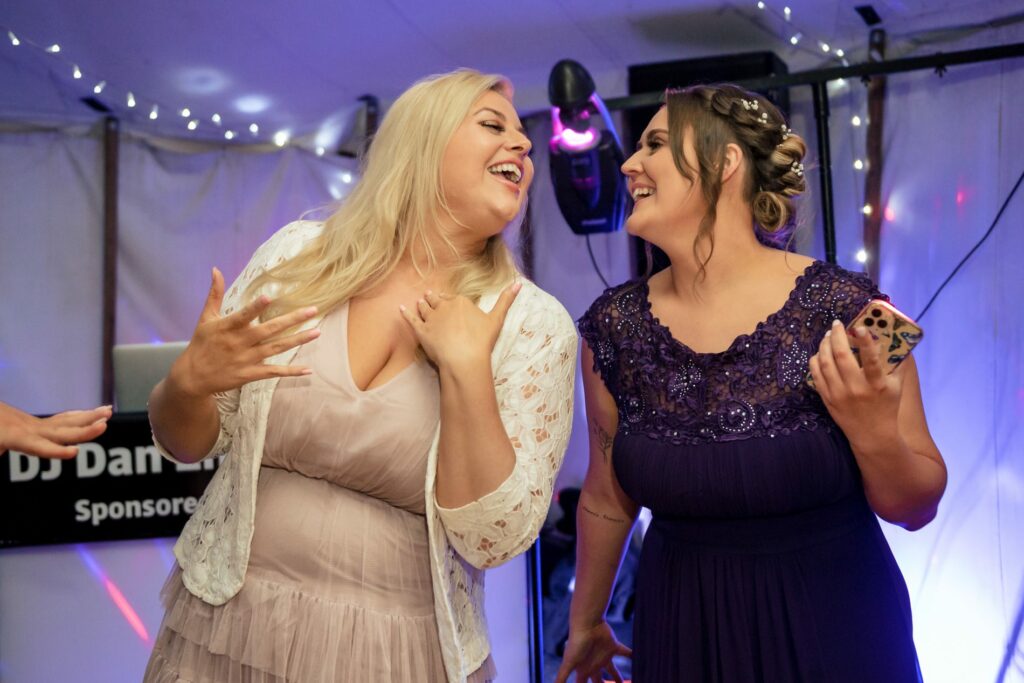 Bridesmaid and wedding guest dance in marquee