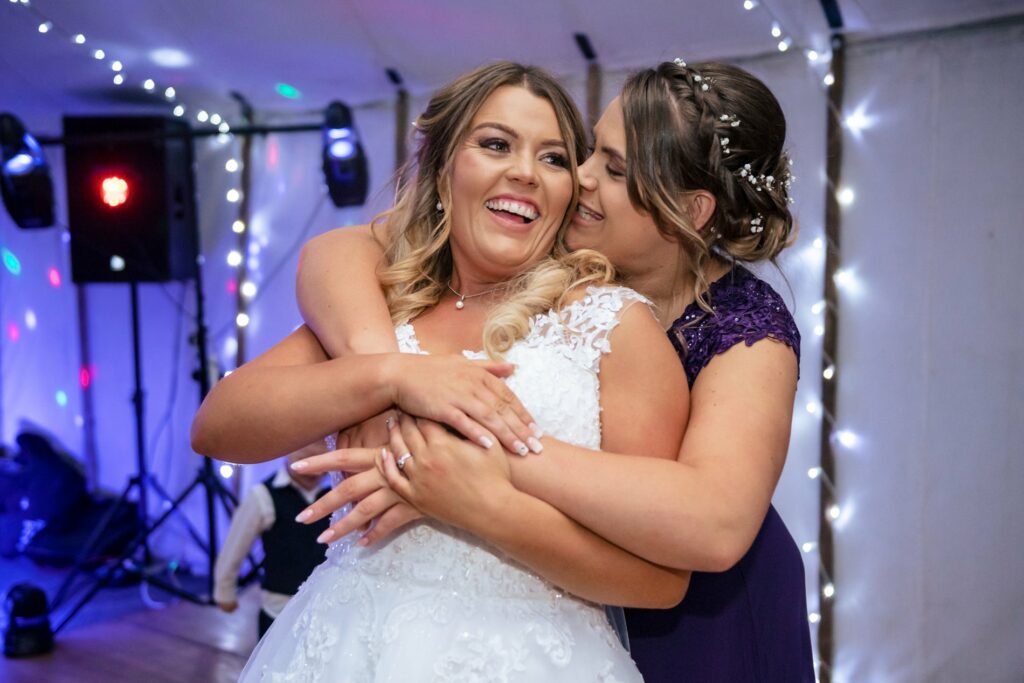 bride and bridesmaids hug on dance floor