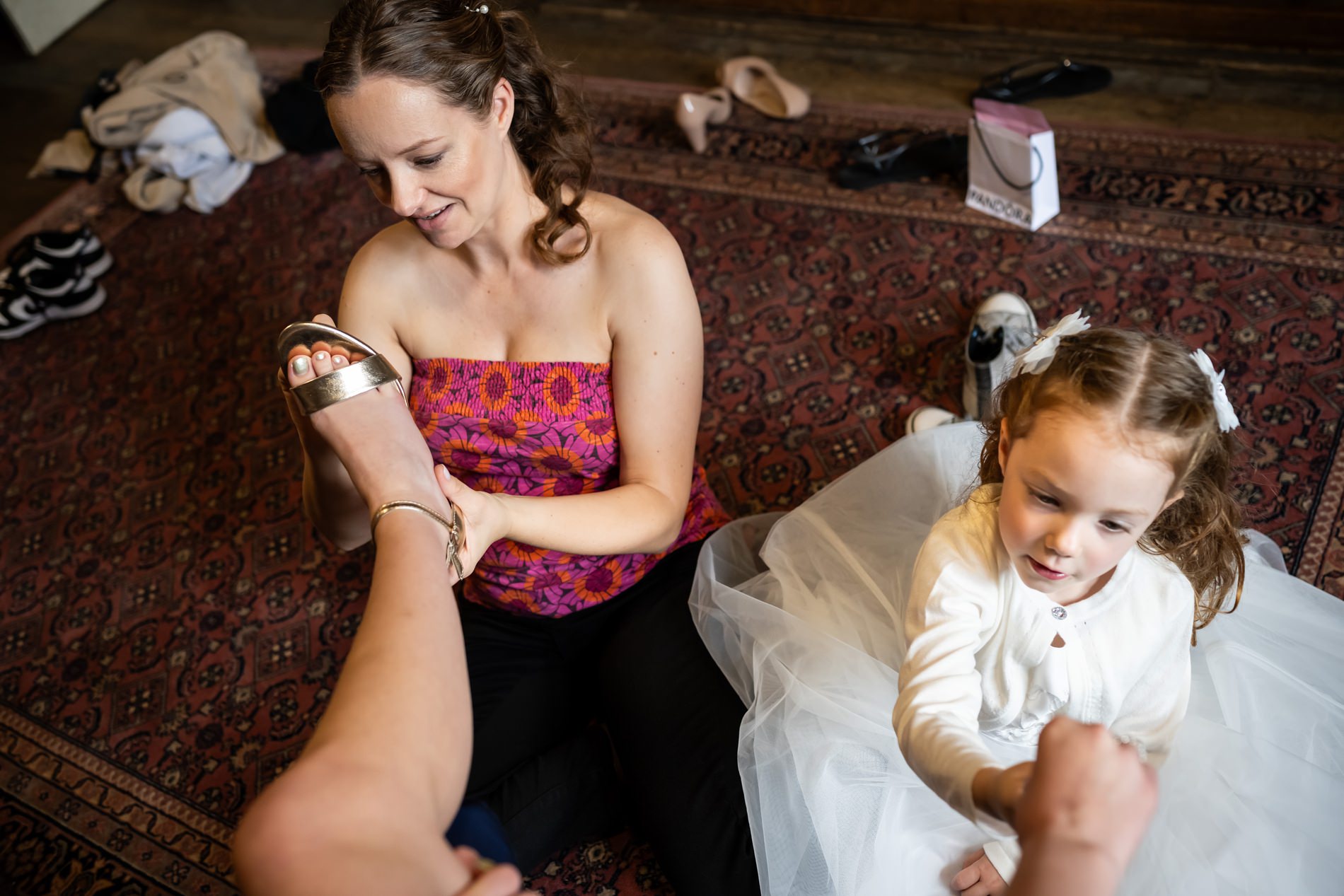 Bride and flower girl help bridesmaid get ready