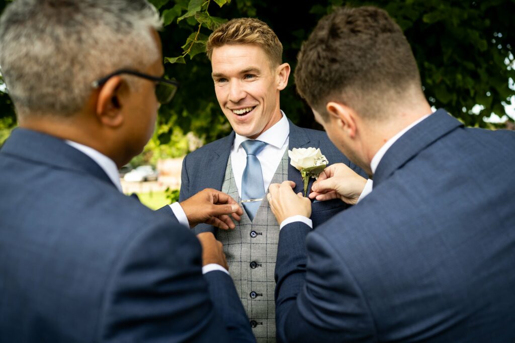 Groom gets button hole pinned on by best men at St Michaels Manor wedding