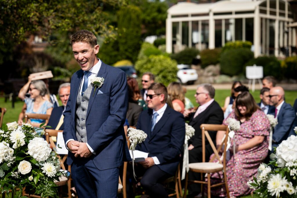 Groom laughs outside St Michaels Manor in the garden waiting for wedding ceremony to begin