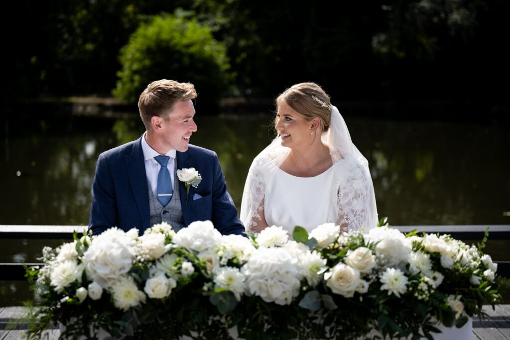 Bride and groom smile at each other during St Michaels Manor wedding ceremony certificate signing