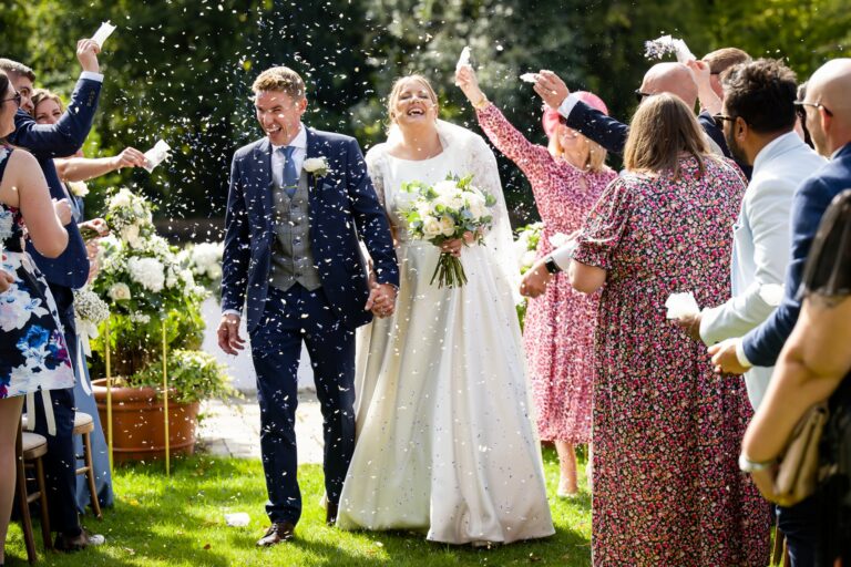 Bride and groom laugh during confetti canon leaving St Michaels Manor outdoor wedding ceremony