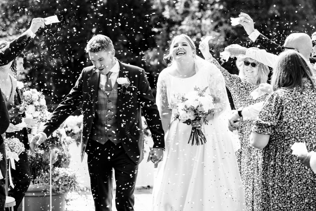 Bride and groom laugh during confetti canon leaving St Michaels Manor outdoor wedding ceremony