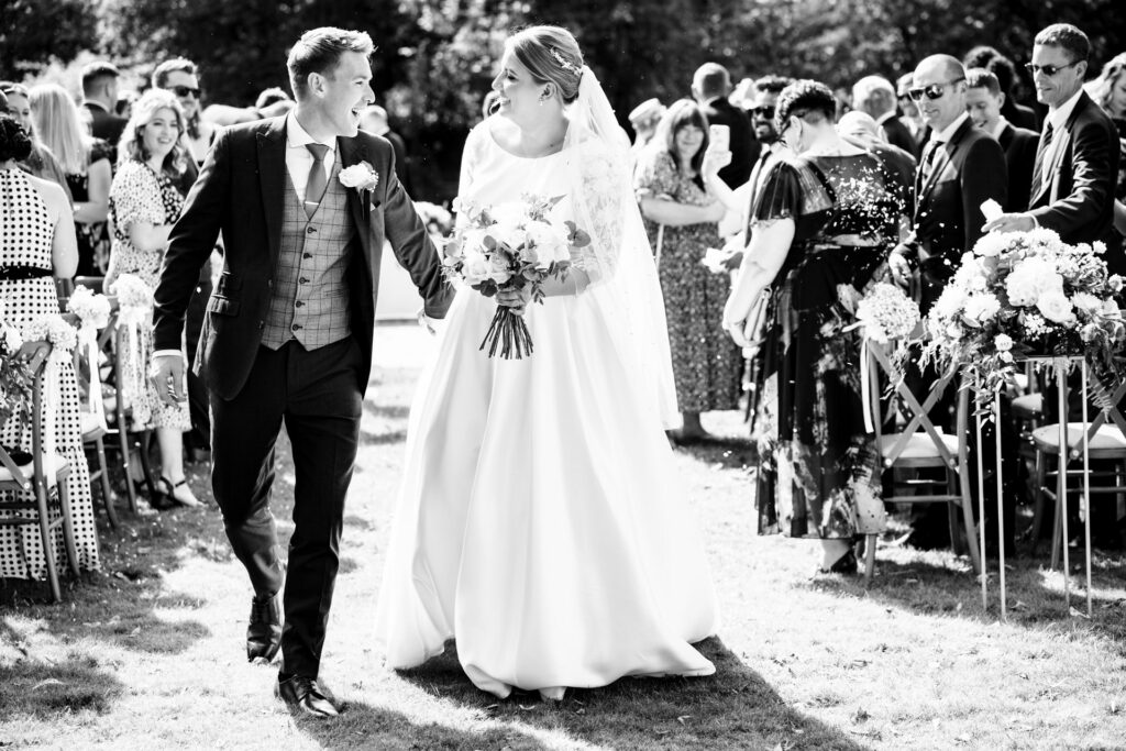Bride and groom smile at each other walking back down the aisle leaving St Michaels Manor outdoor wedding ceremony