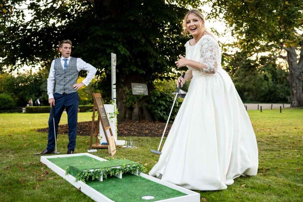Bride laughs while beating groom at mini golf at wedding