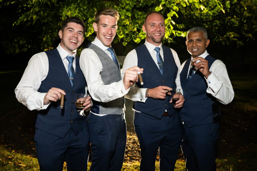 Groom and best men smoke a cigar at the end of the wedding day at St Michaels Manor