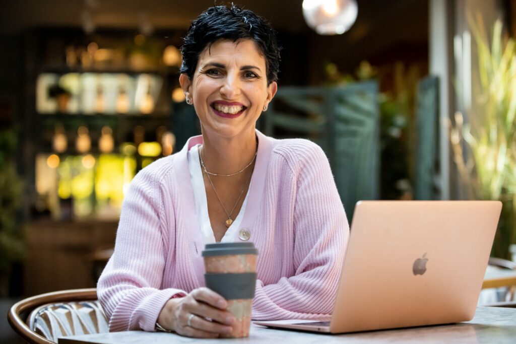 Woman sat at computer with coffee cup in Hertfordshire on branding photography shoot