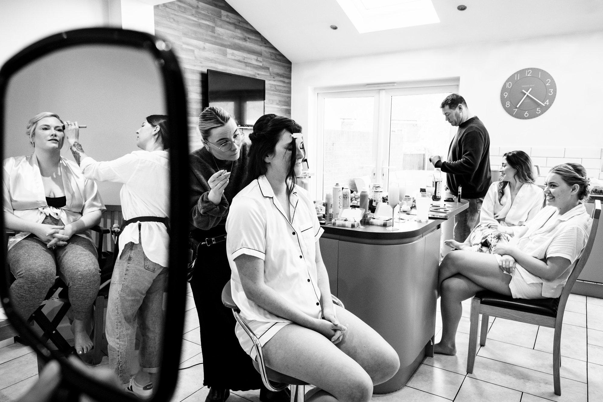 Bridesmaids get makeup done at home in kitchen