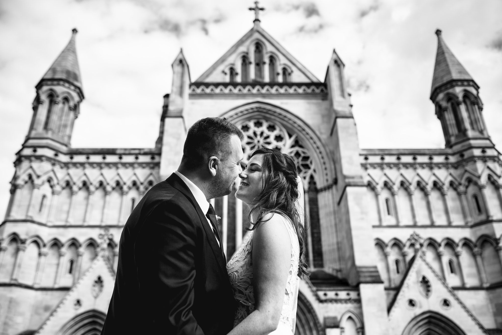 Bride and groom stand in front of St Albans cathedral, Hertfordshire