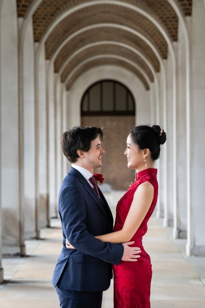 Bride in red dress and groom in suit stand in Hertford Register Office arches