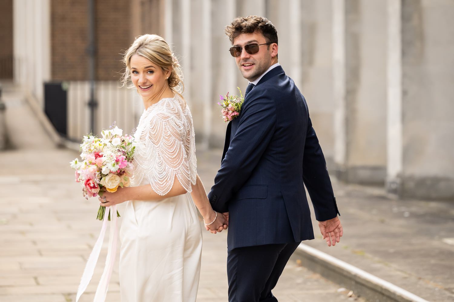 Bride and groom look over their shoulder at camera at Hertford Register Office