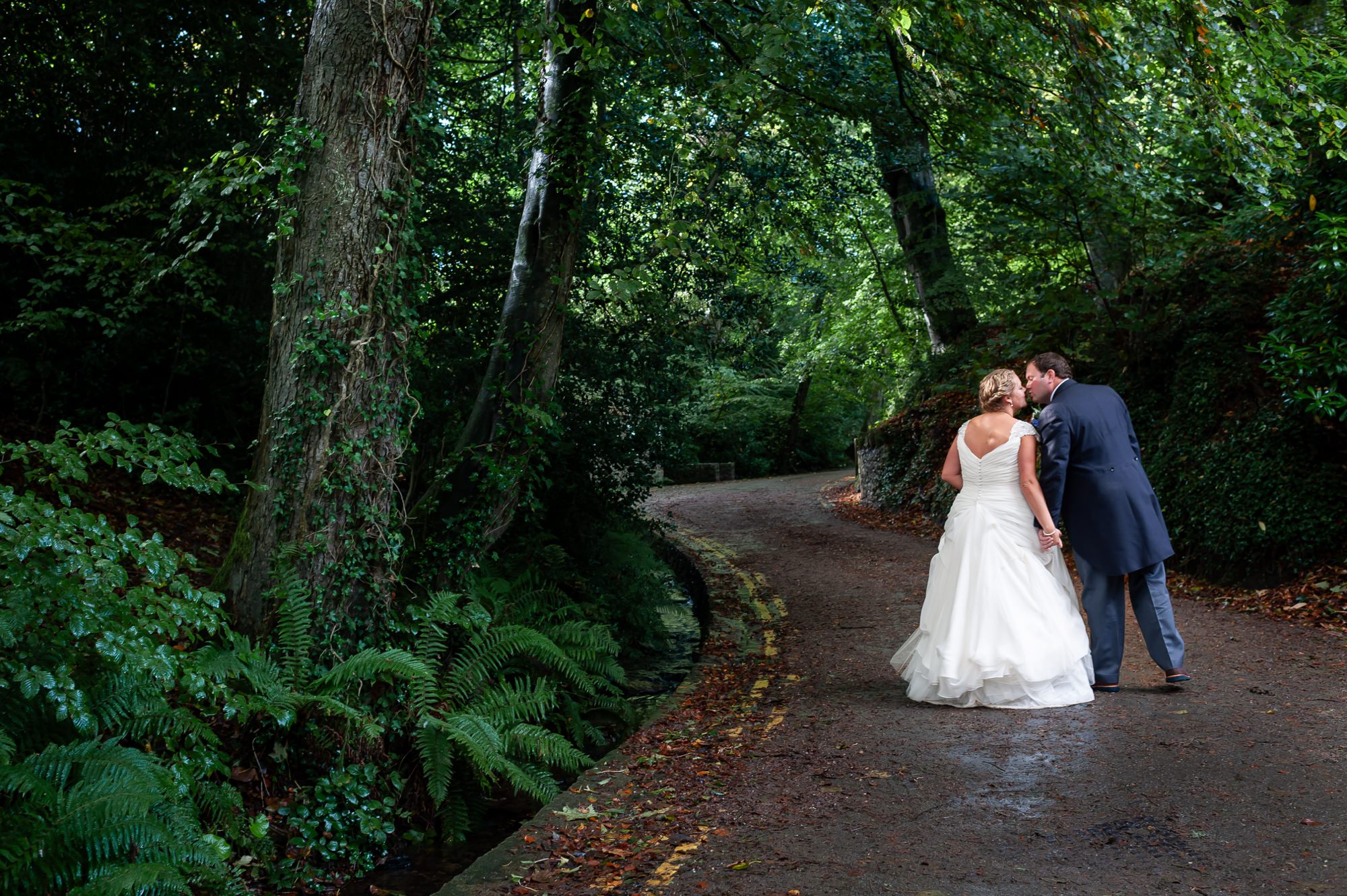 Bride and groom kiss walking up the road in Abersoch, Wales