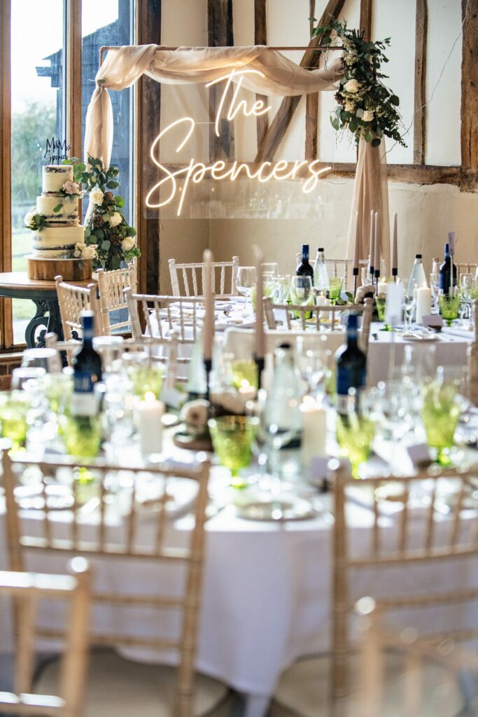 Barn laid out for wedding breakfast with neon sign at Coltsfoot wedding venue Hertfordshire