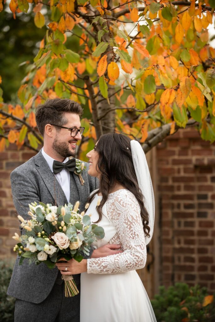 Bride and groom in front of autumn leaves at Coltsfoot wedding venue Hertfordshire