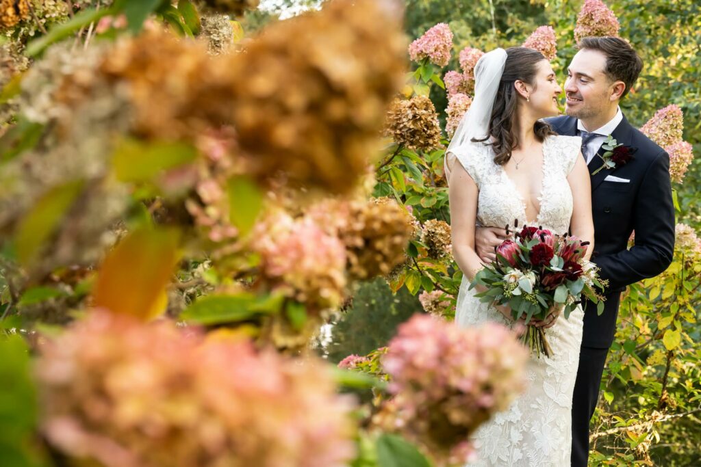 Bride and groom photo through autumnal flowers at St Michael's Manor Hertfordshire