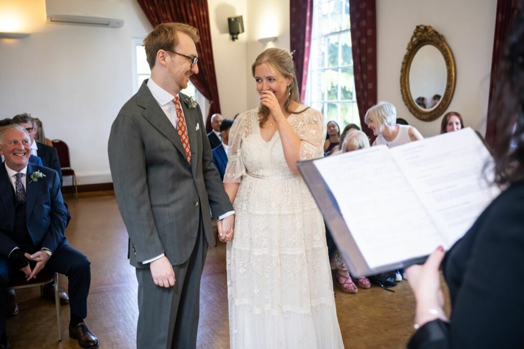 Bride and groom share moment of laughter during vows at Hertford Register office intimate wedding