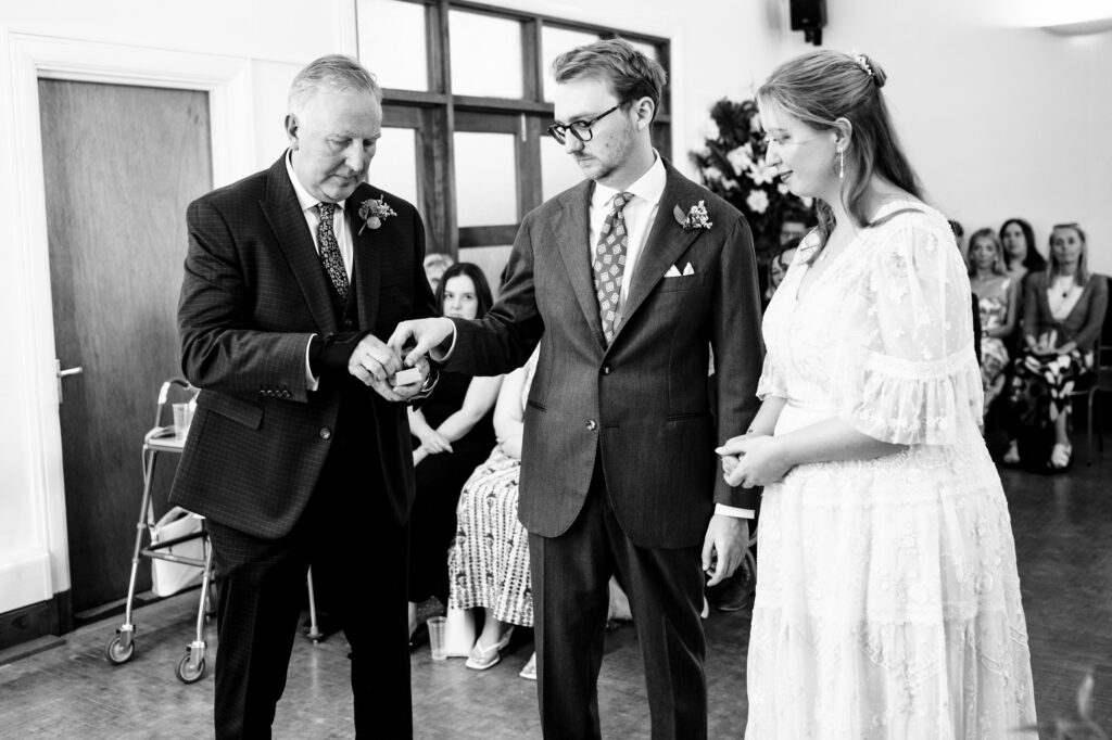 Groom takes ring from father best man during Hertford Register office intimate wedding