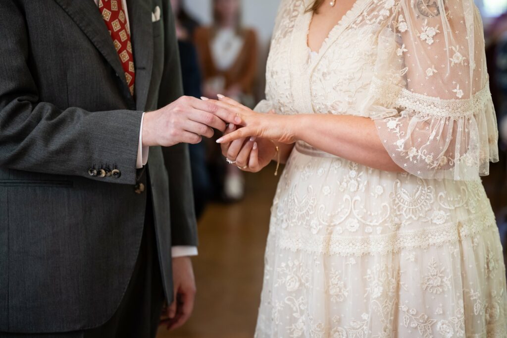 Groom puts ring on brides finger during Hertford Register office intimate wedding