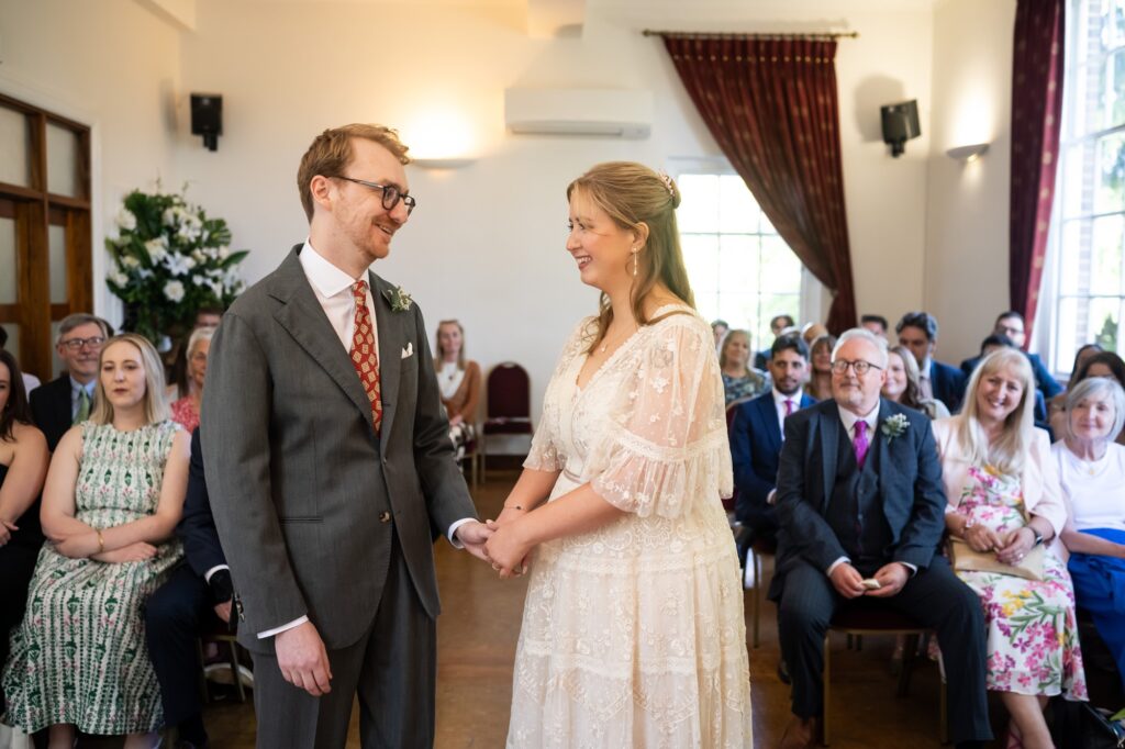 Bride and groom hold hands and smile during Hertford Register office intimate wedding