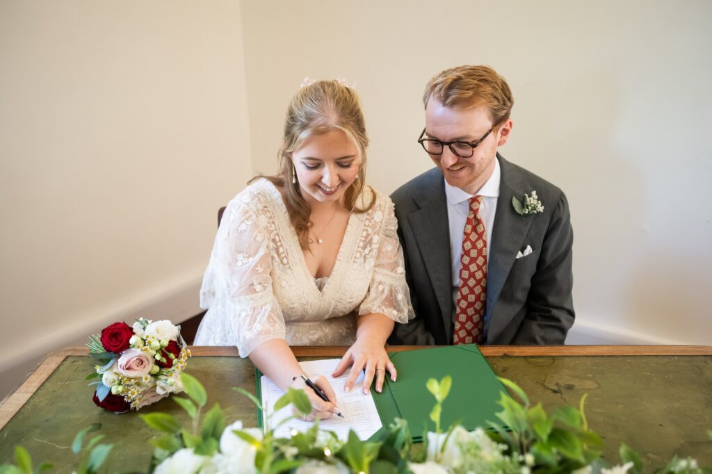 Bride signs register during Hertford Register office intimate wedding
