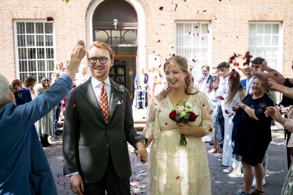 Bride and groom exit Hertford Register office intimate wedding ceremony to bright sunshine and confetti
