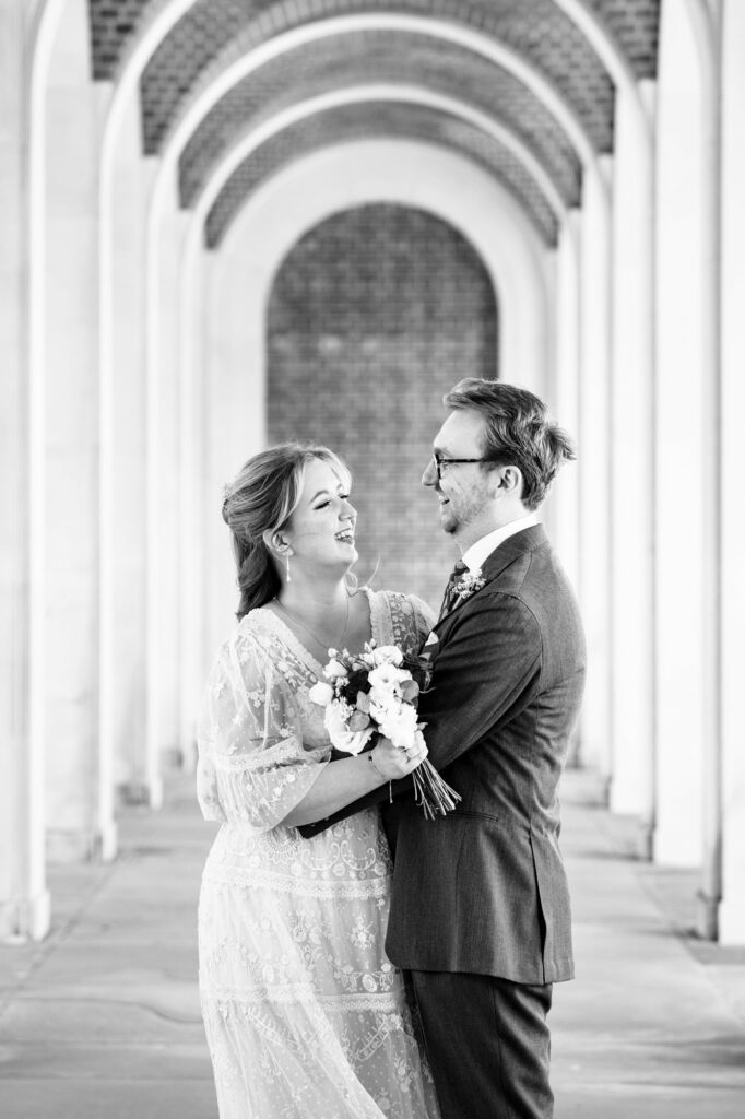 Bride and groom take couple portraits in Hertford Register office white arches after intimate wedding ceremony