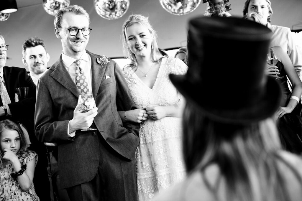 Bride and groom watch best woman make speech at relaxed pub garden wedding reception