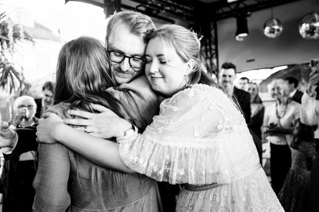 Bride and groom hug best woman after heartfelt speech at pub garden wedding