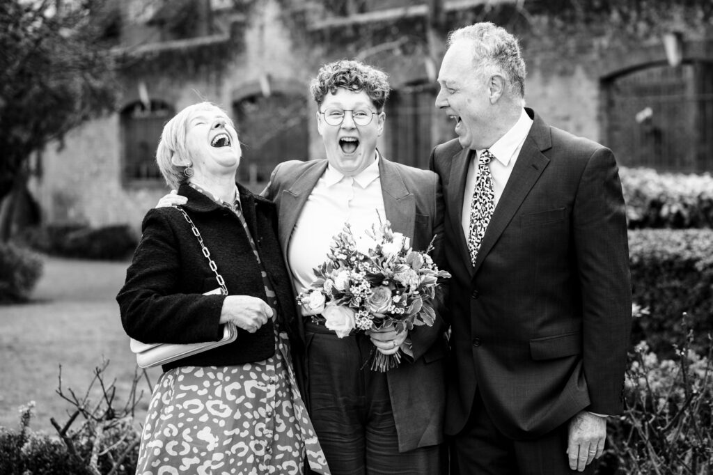 Bride and her parents laugh during family portraits after St Albans Registry Office wedding ceremony