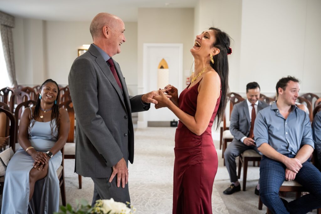 Bride and groom laugh during the ring exchange at intimate St Albans Register Office wedding
