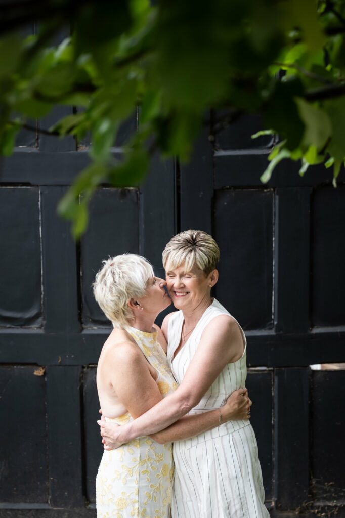 Two brides embrace in St Albans Registry Office gardens after micro wedding ceremony with close family