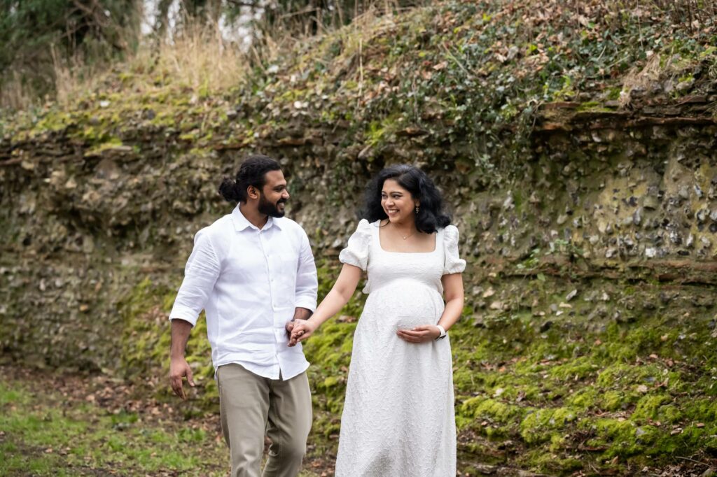 Parents to be walk hand in hand past Roman wall in Verulamium Park St Albans
