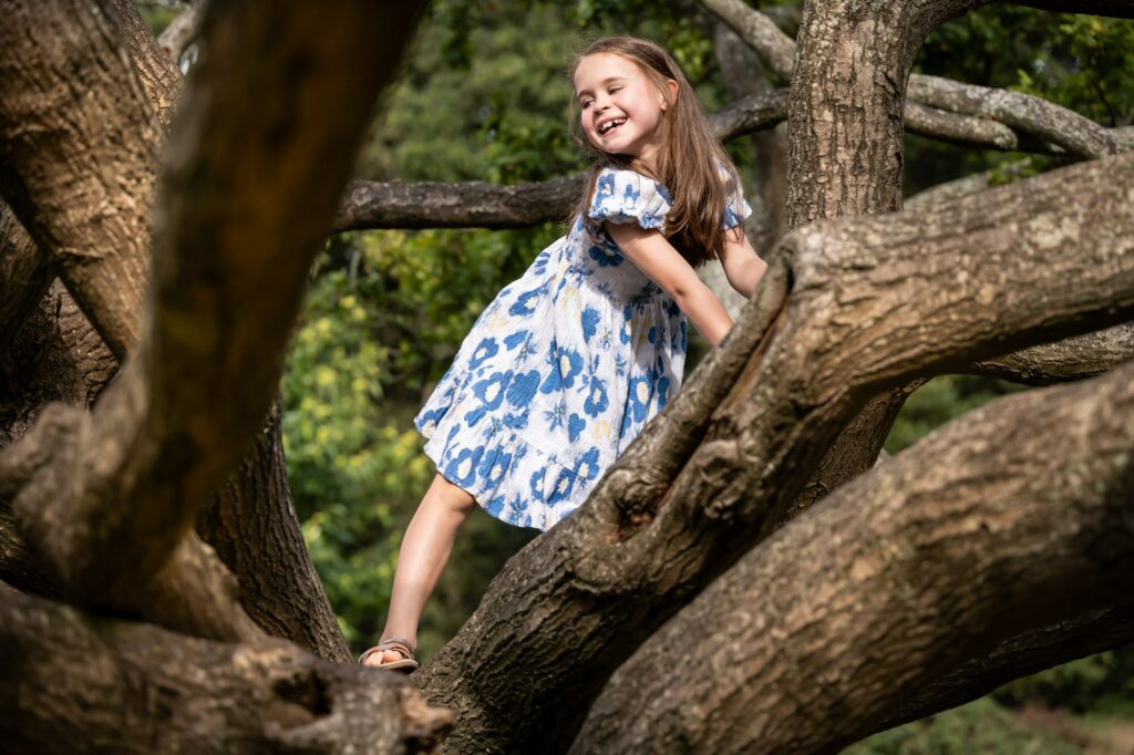Daughter in blue dress climbs tree during family photo shoot in St Albans