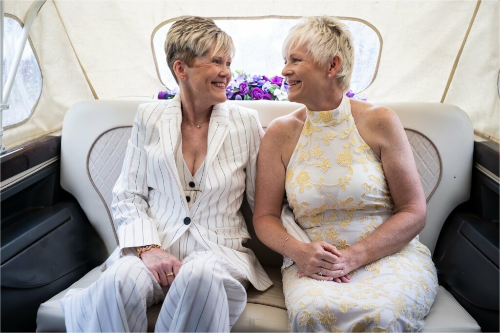 Two brides sit in a taxi waiting for their civil ceremony.
