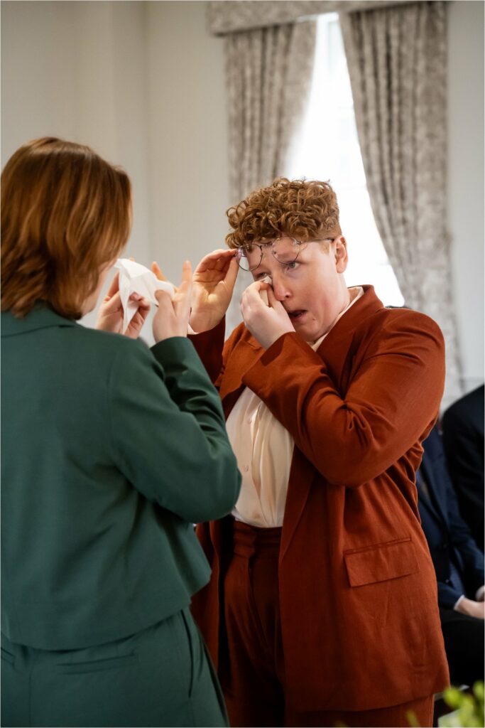 Two brides wipe away tears during emotion filled wedding ceremony.
