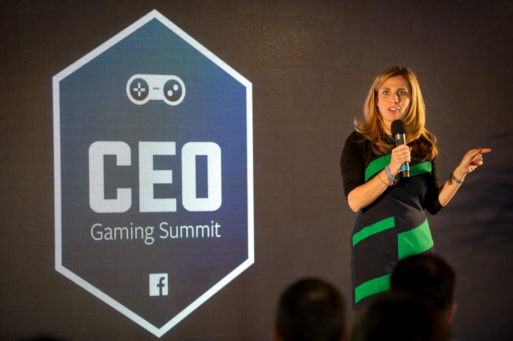 Woman makes speech holding mic on stage at Facebook Gaming Summit.